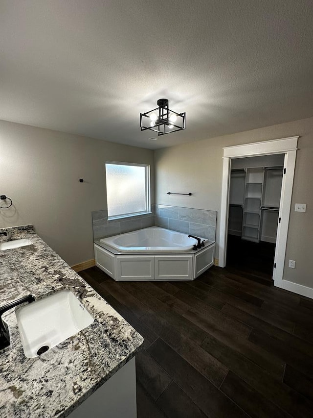 5610 Slayde St, San Angelo, TX 76904 - bathroom with wood finished floors, a garden tub, baseboards, double vanity, and a textured ceiling