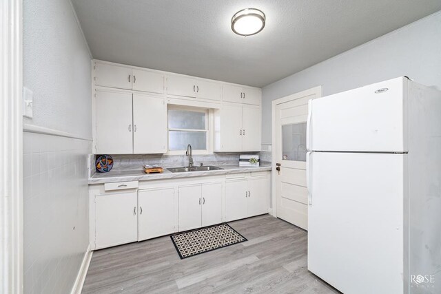 kitchen with sink, white cabinetry, white refrigerator, decorative backsplash, and light wood-type flooring