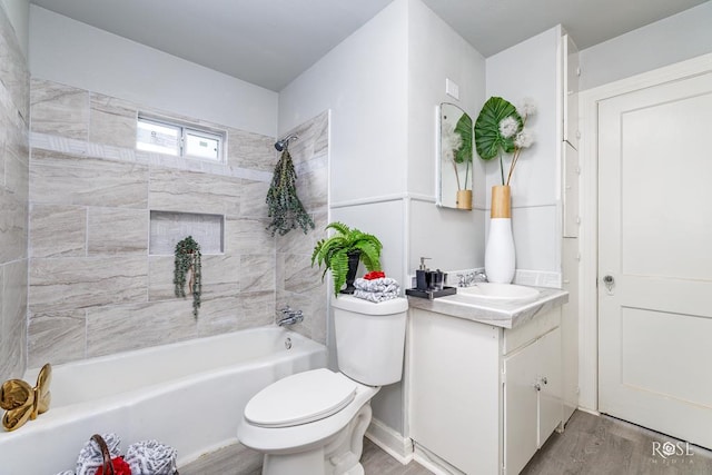 full bathroom with hardwood / wood-style flooring, vanity, tiled shower / bath combo, and toilet