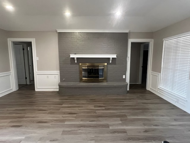 unfurnished living room with hardwood / wood-style flooring and a brick fireplace