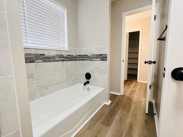 bathroom featuring hardwood / wood-style floors and a tub to relax in