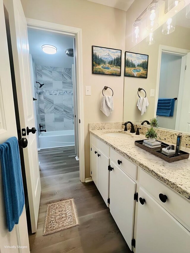 bathroom with hardwood / wood-style flooring, vanity, and tiled shower / bath