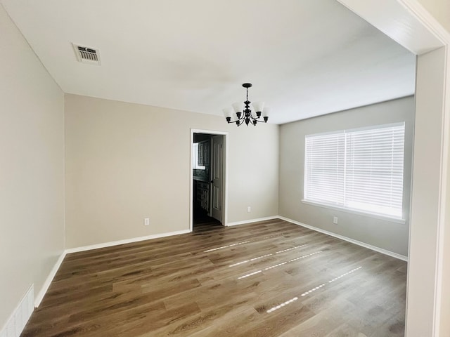 spare room featuring an inviting chandelier and hardwood / wood-style flooring