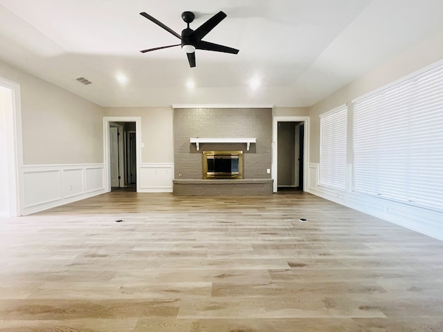 unfurnished living room with a brick fireplace, light hardwood / wood-style flooring, and ceiling fan