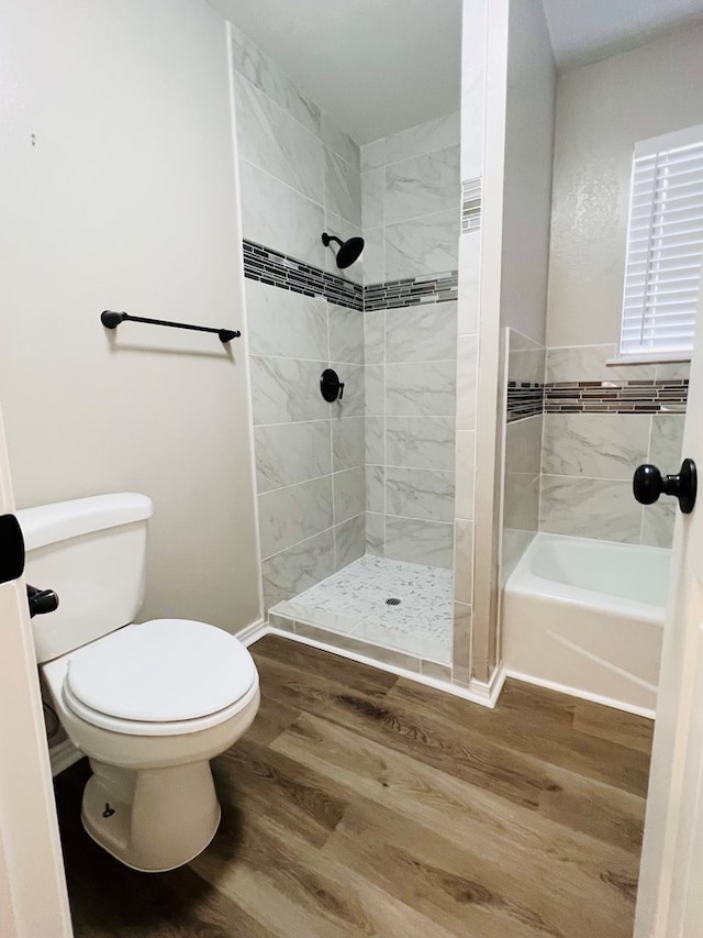 bathroom with hardwood / wood-style flooring, tiled shower, and toilet