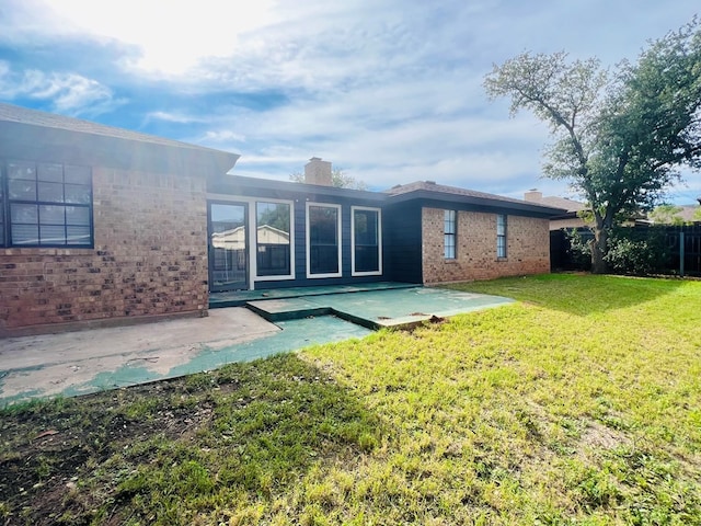 back of house with a patio and a lawn