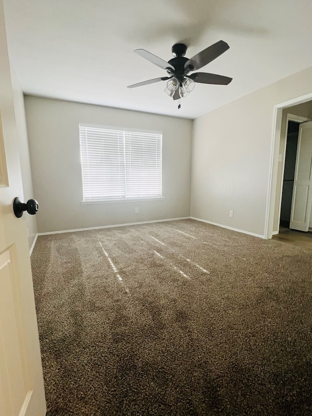 empty room with ceiling fan and dark carpet