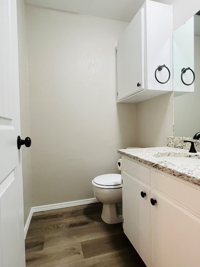 bathroom with toilet, vanity, and wood-type flooring