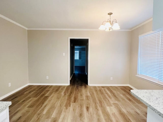 spare room featuring wood-type flooring, an inviting chandelier, and crown molding