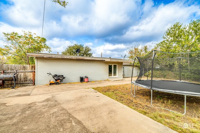 back of property with a trampoline and a patio area