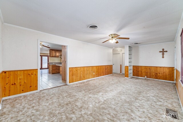 unfurnished room featuring ornamental molding, light carpet, a textured ceiling, and ceiling fan