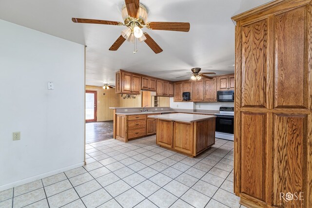 kitchen featuring electric stove, light tile patterned floors, ceiling fan, and a kitchen island