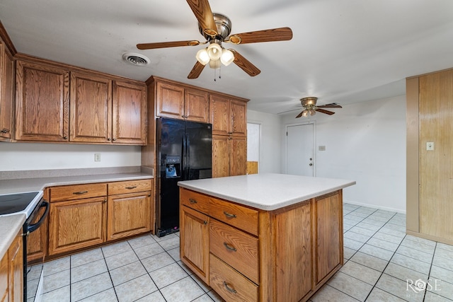 kitchen with light tile patterned flooring, black fridge, built in desk, electric range, and a kitchen island