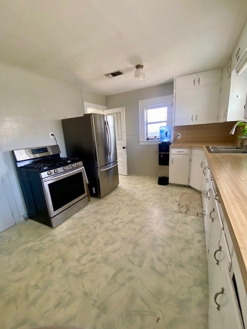 925 E 40th St, San Angelo, TX 76903 - kitchen with appliances with stainless steel finishes, a sink, white cabinets, and wooden counters