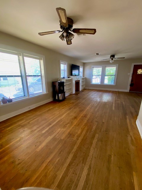 925 E 40th St, San Angelo, TX 76903 - unfurnished living room featuring ceiling fan, wood finished floors, baseboards, and a fireplace