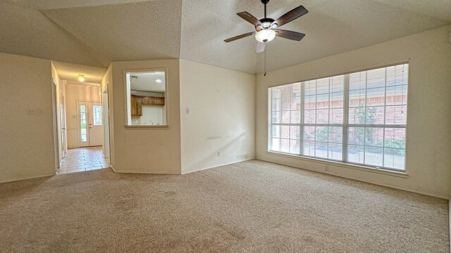 unfurnished room with lofted ceiling, carpet flooring, a ceiling fan, and a textured ceiling