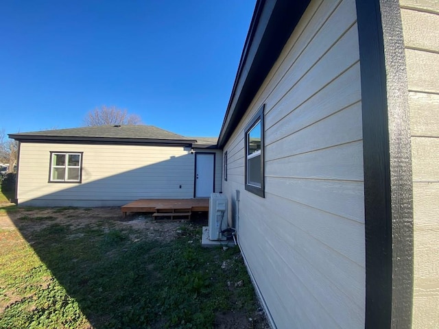 view of property exterior featuring a wooden deck, ac unit, and a lawn