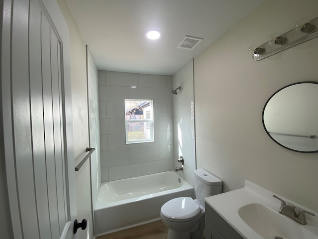 full bathroom featuring tiled shower / bath combo, vanity, and toilet