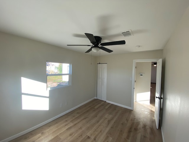 unfurnished bedroom featuring hardwood / wood-style flooring, ceiling fan, and a closet