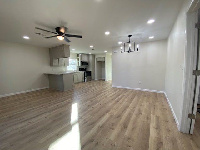 unfurnished living room with ceiling fan with notable chandelier and light wood-type flooring