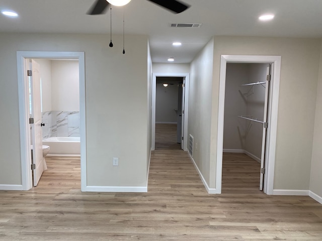 unfurnished bedroom with a walk in closet, a closet, ensuite bath, and light wood-type flooring