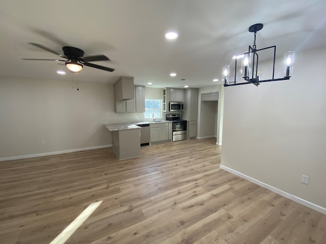 kitchen with appliances with stainless steel finishes, sink, gray cabinetry, hanging light fixtures, and light wood-type flooring