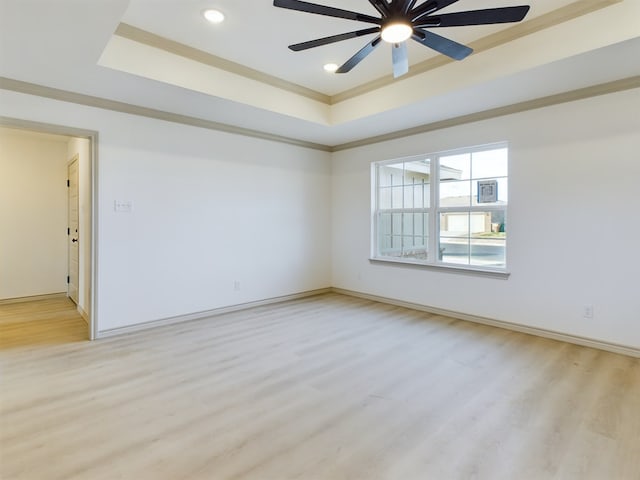 spare room with crown molding, light hardwood / wood-style flooring, ceiling fan, and a tray ceiling