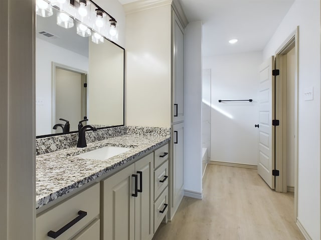 bathroom featuring hardwood / wood-style flooring, vanity, and bathing tub / shower combination