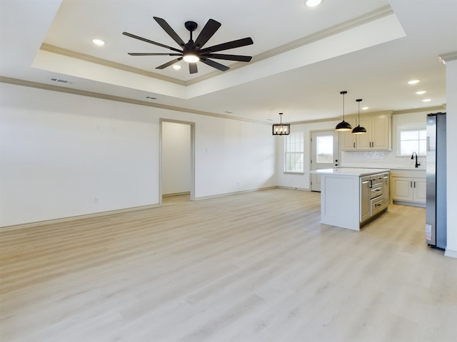 kitchen featuring crown molding, stainless steel fridge, a raised ceiling, and a kitchen island