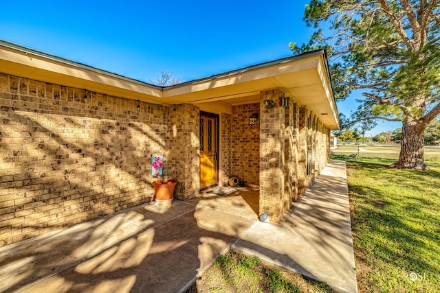 property entrance with a lawn and a patio