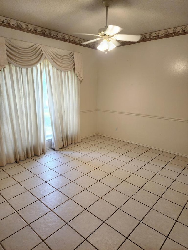spare room with a textured ceiling, ceiling fan, and light tile patterned floors