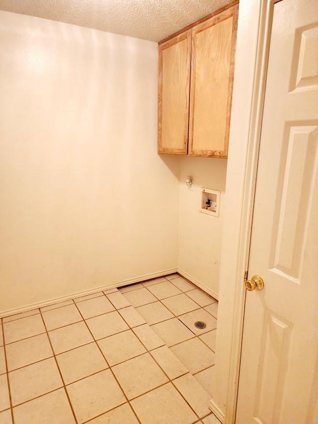 clothes washing area with light tile patterned floors, baseboards, cabinet space, washer hookup, and a textured ceiling