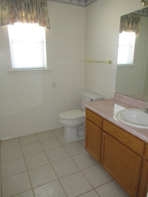 bathroom with vanity, toilet, a healthy amount of sunlight, and tile patterned flooring