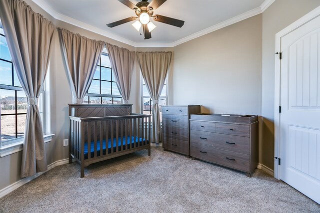 bedroom with ceiling fan, ornamental molding, light colored carpet, and a crib