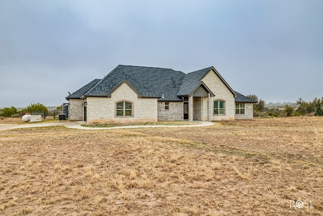 french country inspired facade with a front yard and central air condition unit