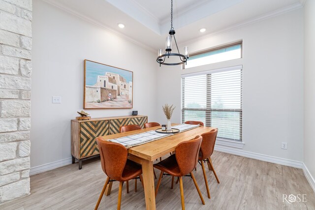 dining room featuring a raised ceiling, ornamental molding, an inviting chandelier, and light hardwood / wood-style floors