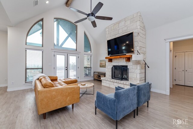 living room with high vaulted ceiling, a fireplace, light hardwood / wood-style floors, and french doors