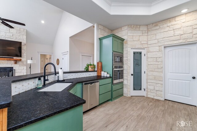 kitchen featuring sink, green cabinets, stainless steel appliances, light hardwood / wood-style floors, and a stone fireplace