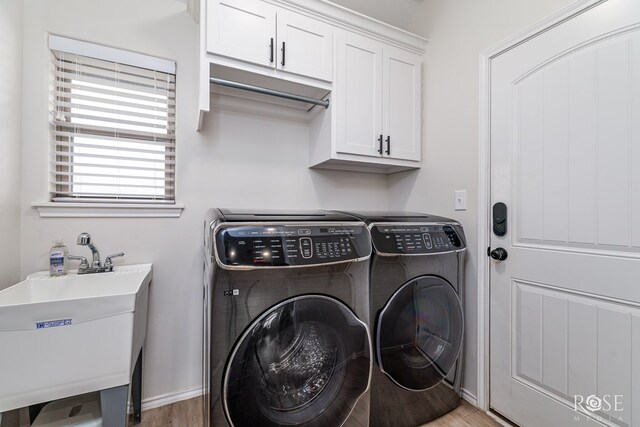 clothes washing area featuring cabinets, hardwood / wood-style flooring, sink, and washer and clothes dryer