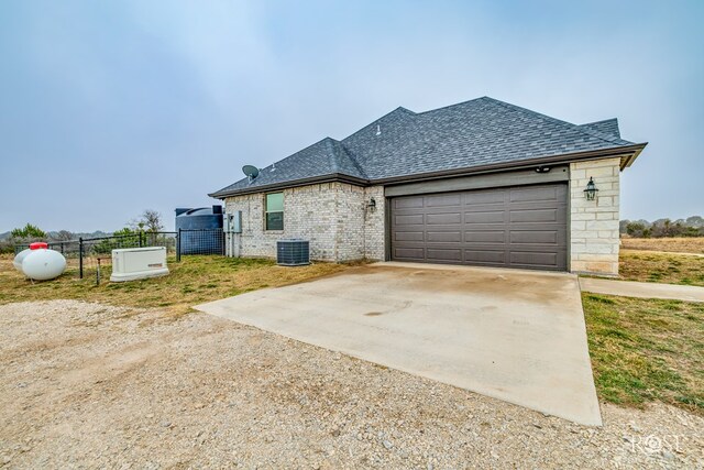 french country home with cooling unit and a garage