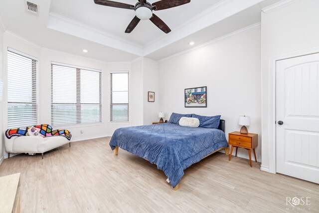 bedroom featuring crown molding, a tray ceiling, light hardwood / wood-style flooring, and ceiling fan