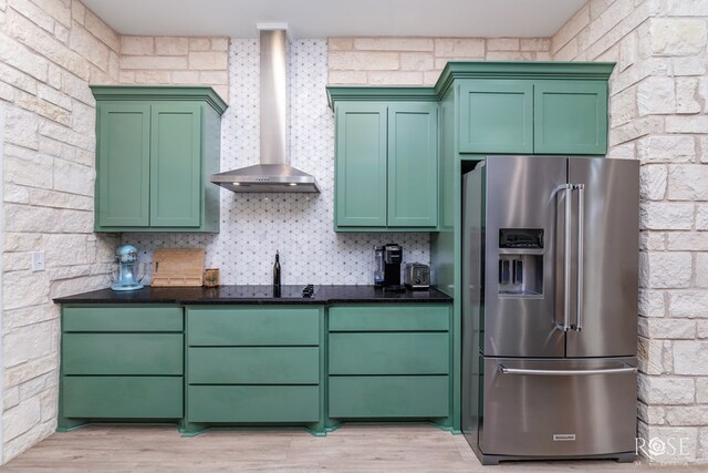 kitchen with high end fridge, wall chimney exhaust hood, and green cabinets