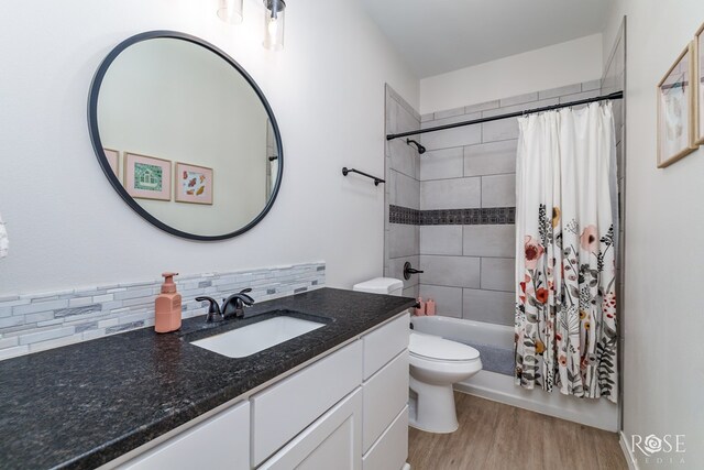 full bathroom with hardwood / wood-style floors, backsplash, vanity, shower / tub combo, and toilet