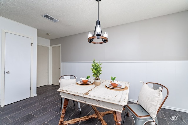 dining space with an inviting chandelier and a textured ceiling