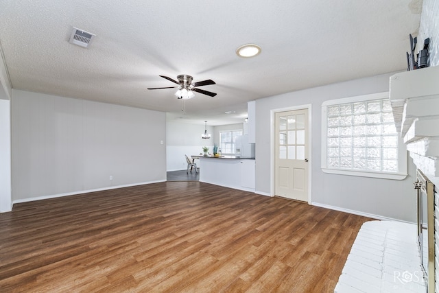 unfurnished living room featuring ceiling fan, wood-type flooring, a textured ceiling, and a fireplace