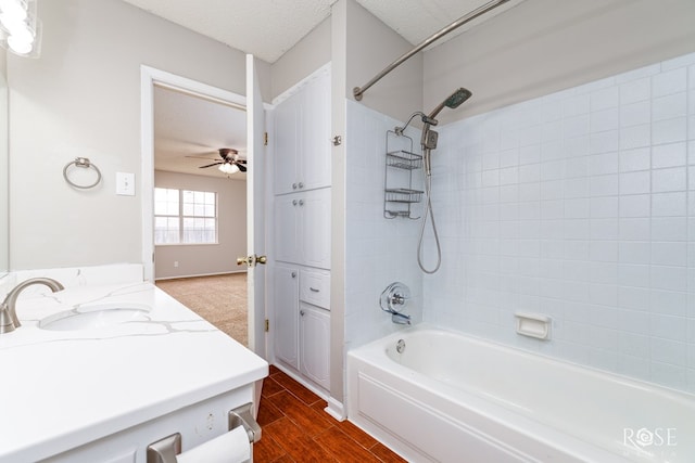 bathroom featuring ceiling fan, vanity, tiled shower / bath, and a textured ceiling