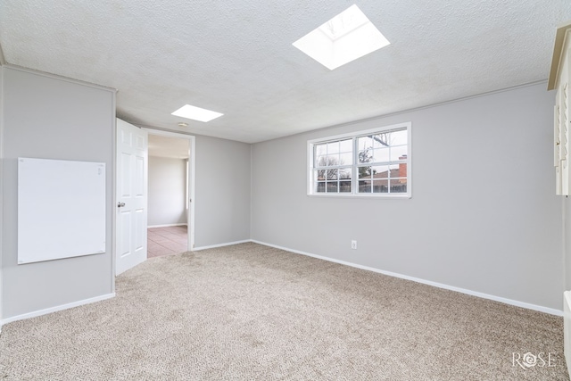 carpeted spare room featuring a textured ceiling and a skylight