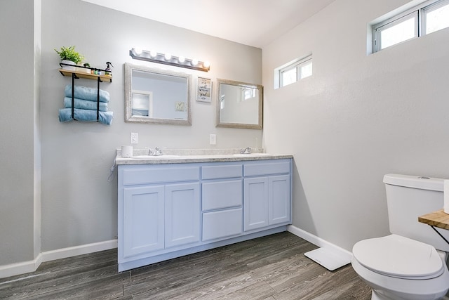 419 N Emerson St, San Angelo, TX 76903 - bathroom featuring toilet, wood finished floors, baseboards, and double vanity
