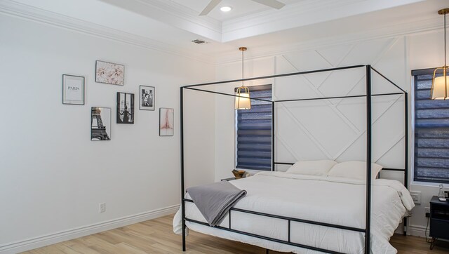 bedroom featuring a tray ceiling, crown molding, ceiling fan, and hardwood / wood-style flooring