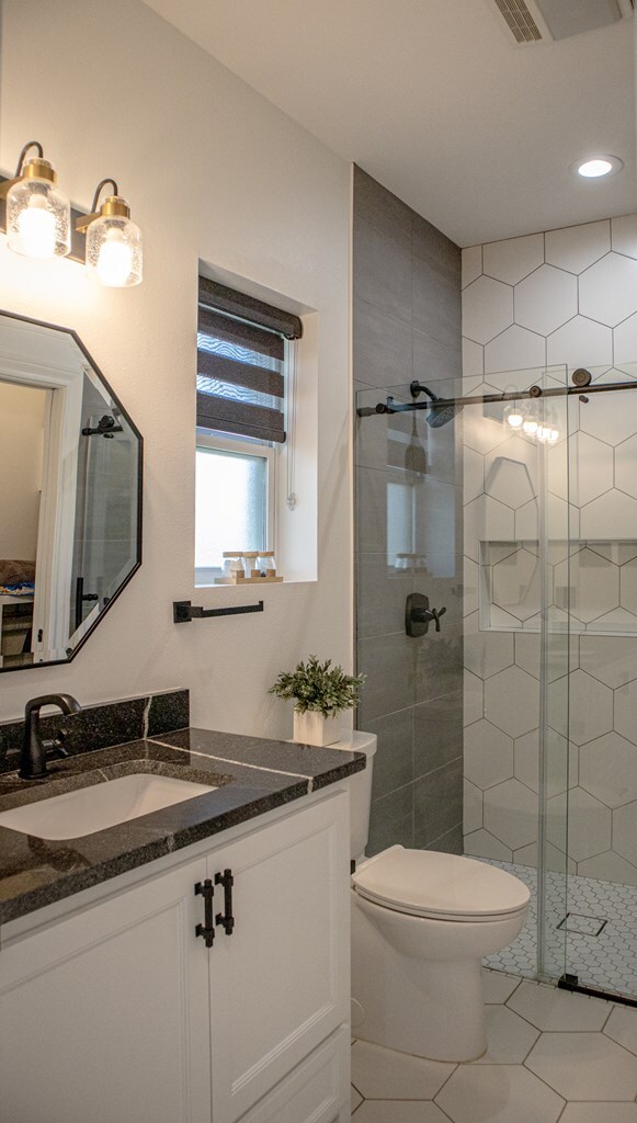 bathroom featuring vanity, tile patterned flooring, toilet, and walk in shower